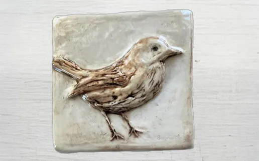 Ceramic relief of a bird perched on a textured, square tile, showcasing intricate details in its feathers and form. Ideal for decorative or artistic contexts.Ceramic relief of a bird perched on a textured, square tile, showcasing intricate details in its feathers and form. Ideal for decorative or artistic contexts.