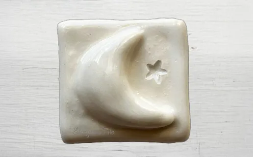 White ceramic plaque featuring a crescent moon and star design, evoking a serene nighttime theme. Ideal for decorative or gift purposes.