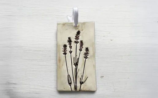Pressed lavender flowers are depicted on a rectangular pendant, highlighting their delicate beauty against a neutral background.