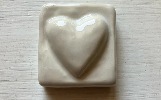 Glossy, white ceramic square dish featuring a raised heart shape, symbolizing love and affection, ideal for decorative or functional use.