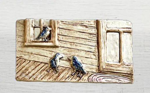 Ceramic relief depicting three bluebirds near a wooden window and door, symbolizing connection with nature and home decor themes.
