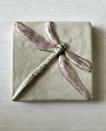 Clay tile featuring a beautifully crafted dragonfly design with delicate pink and gray details, highlighting artistic craftsmanship.
