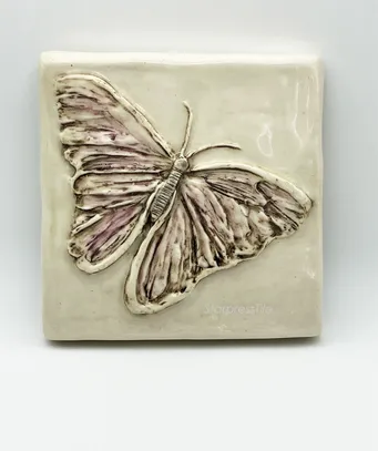 Ceramic wall art featuring a finely detailed embossed butterfly design in soft pastel colors, highlighting craftsmanship and nature's beauty.