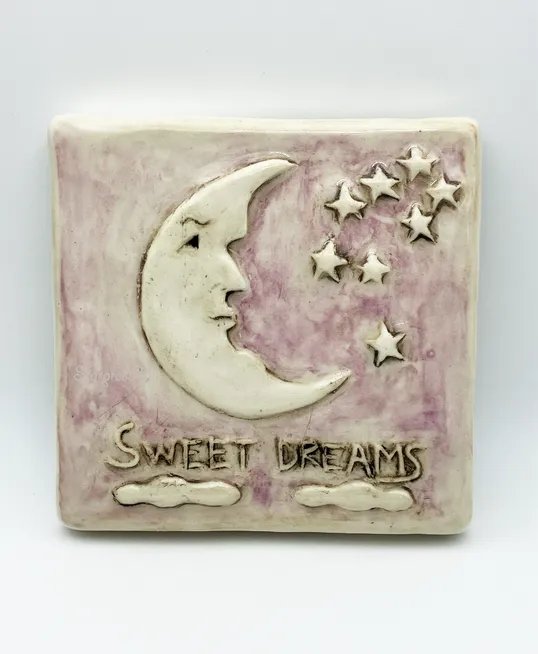 Ceramic wall art featuring a crescent moon, stars, and the phrase "Sweet Dreams" against a lavender background, symbolizing nighttime serenity.