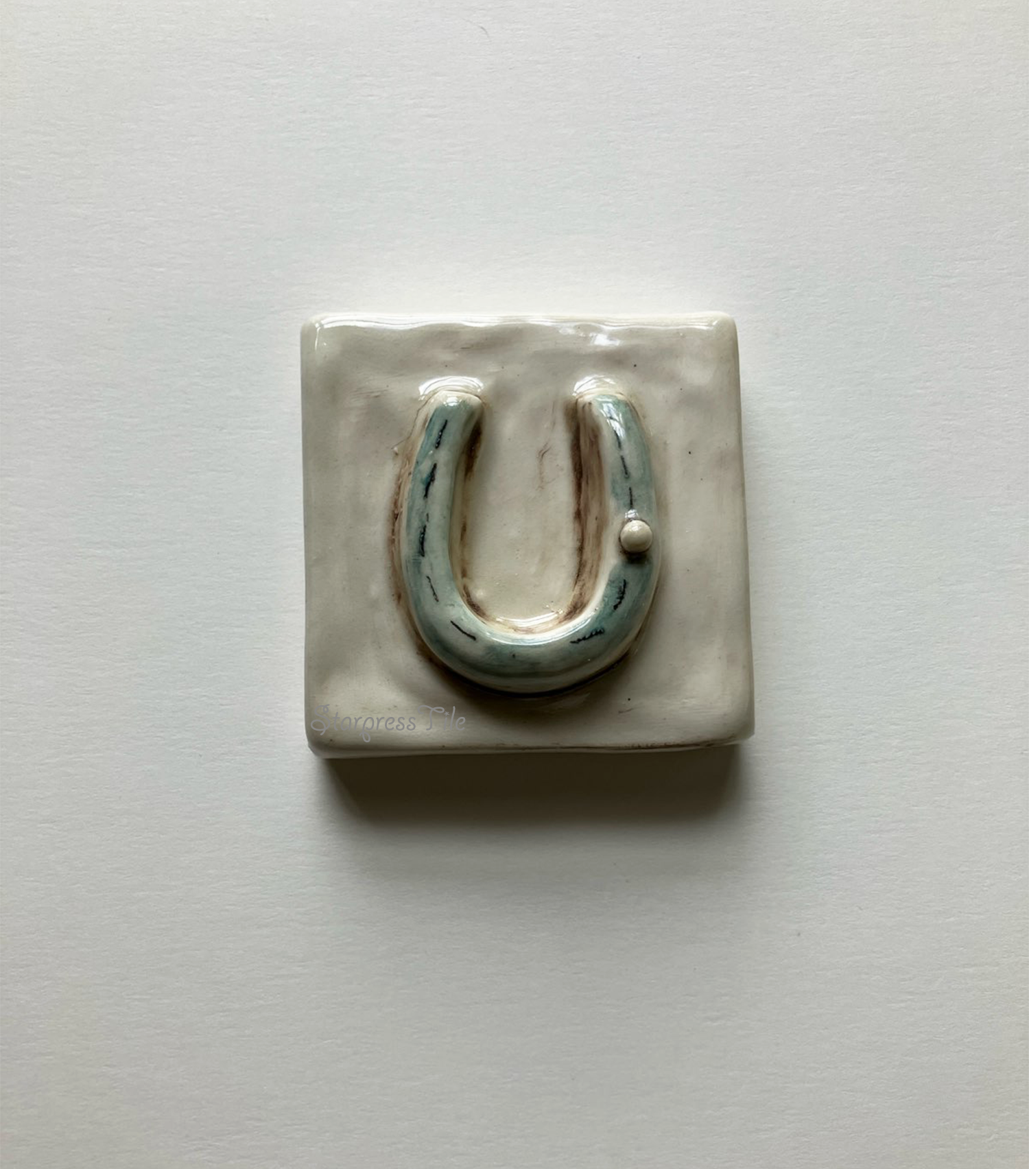 Horseshoe ceramic art tile, hand painted in teal and brown highlight glaze.